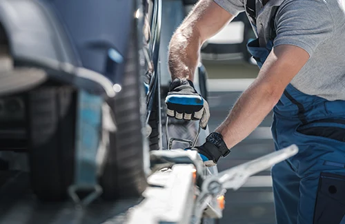 Vehicle being secured to an open auto transport trailer