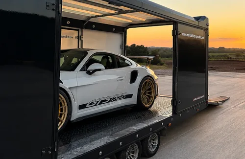 Sports car being loaded into an enclosed auto transport trailer